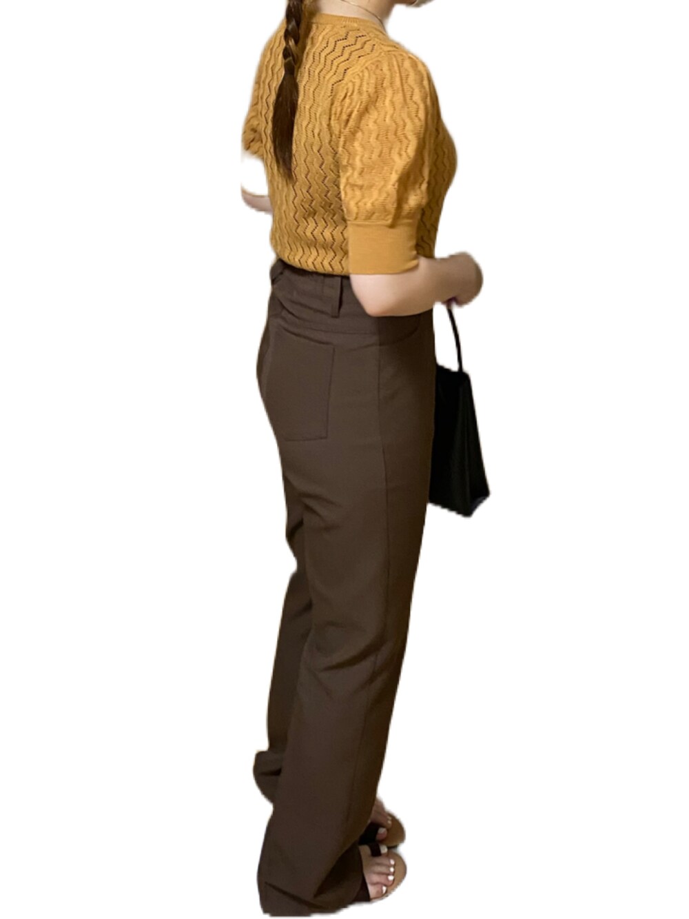 オレンジ系のトップス、ブラウン系のスラックス、ブラック系のハンドバッグを着用したレディースの夏コーディネートの3枚目の写真