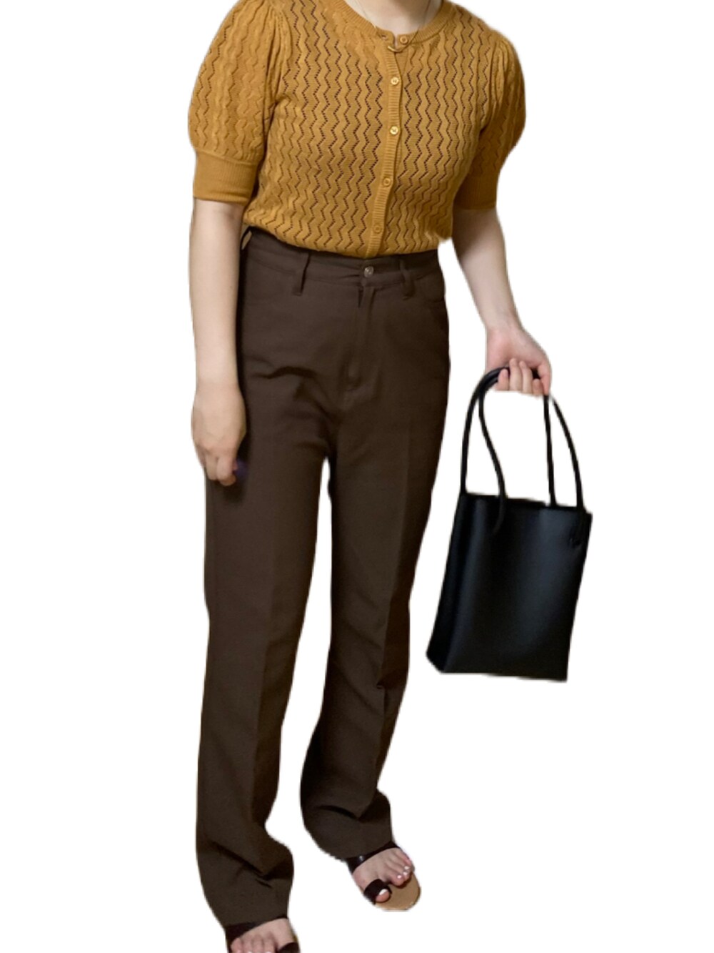 オレンジ系のトップス、ブラウン系のスラックス、ブラック系のハンドバッグを着用したレディースの夏コーディネートの2枚目の写真