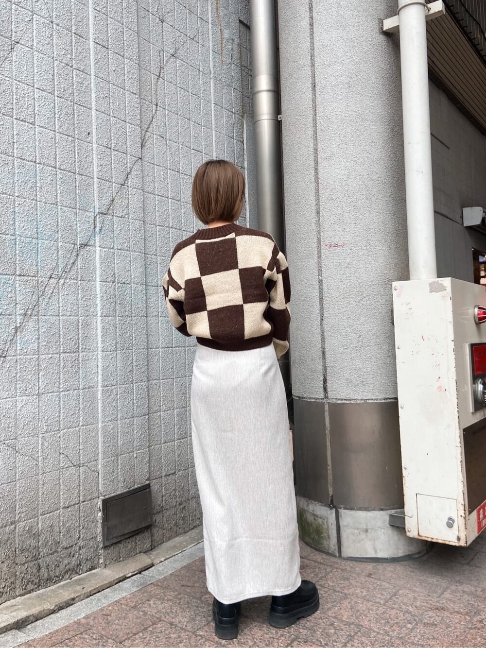 ホワイト系のスカート、ベージュ系のハンドバッグ、ブラウン系のカーディガン/ボレロを着用したレディースの冬コーディネートの2枚目の写真