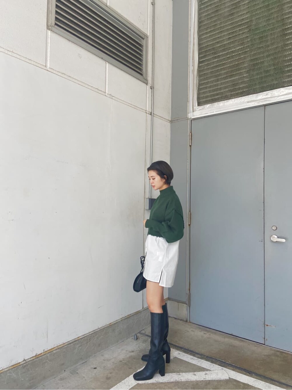 ブラック系のスカート、ブラック系のブーツ、ホワイト系のシャツ/ブラウスを着用したレディースの秋コーディネートの2枚目の写真