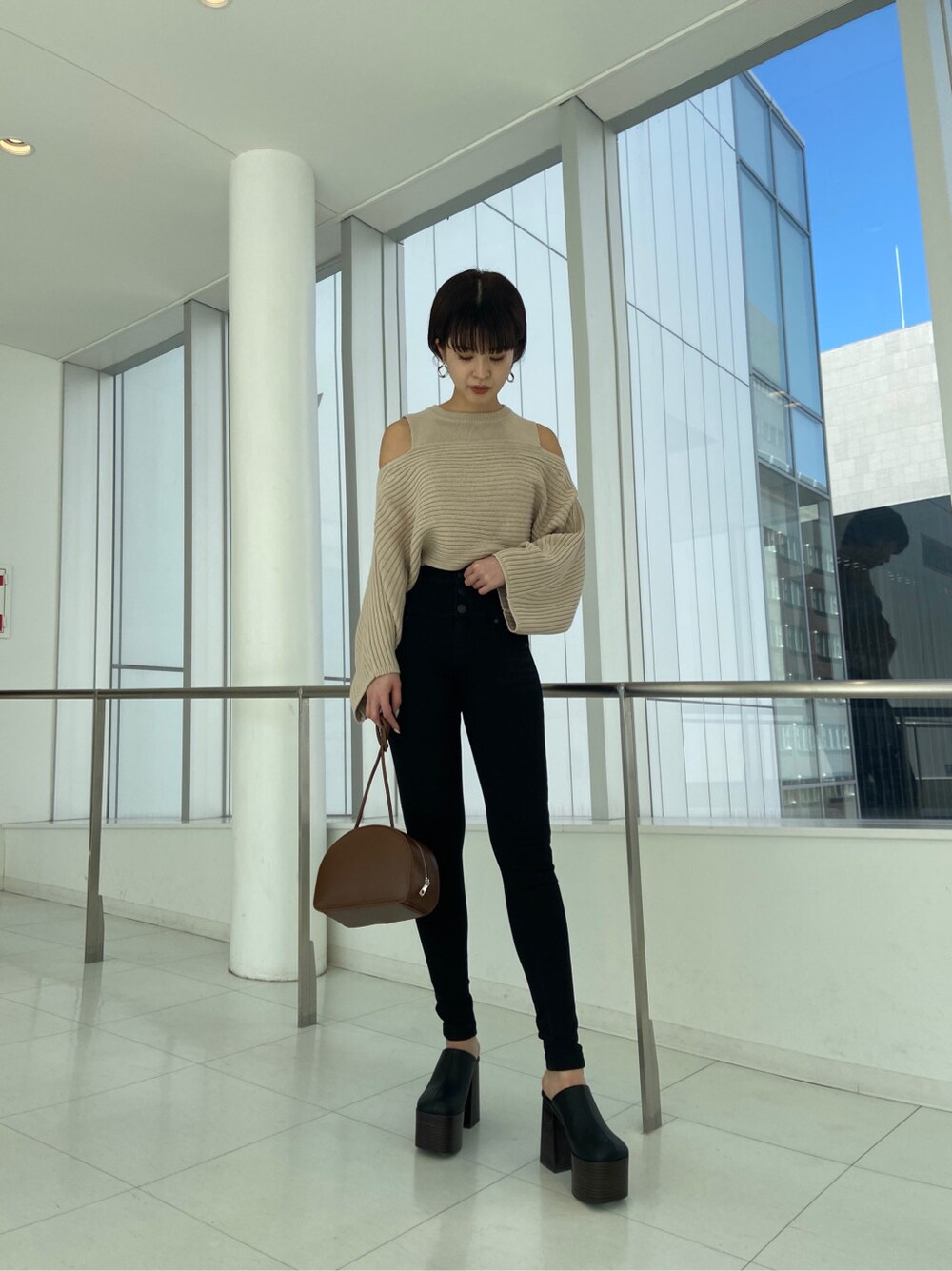 ブラウン系のショルダーバッグ、ブラック系のデニムパンツ、ベージュ系のニット/セーターを着用したレディースの冬コーディネートの3枚目の写真