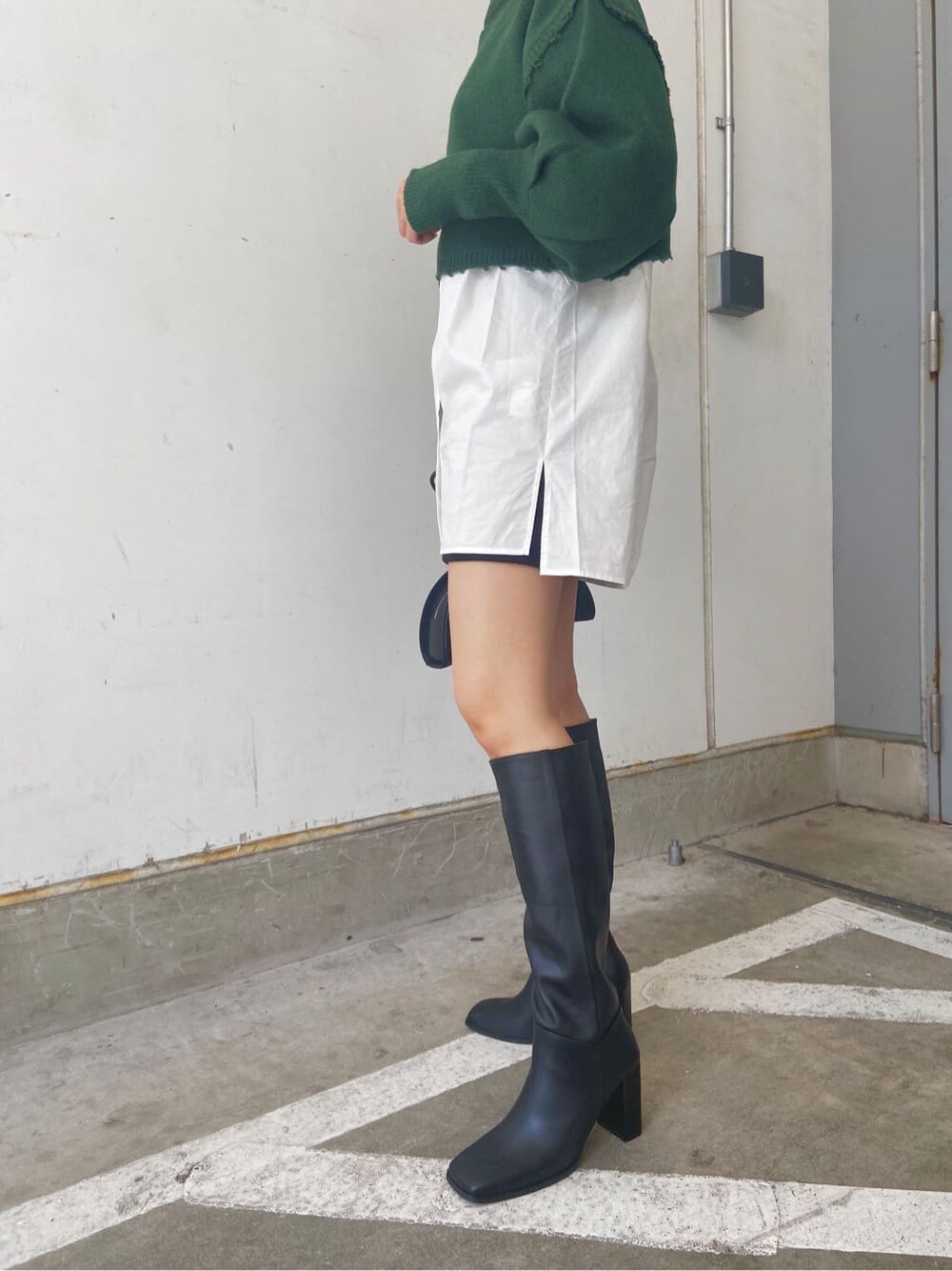 ブラック系のスカート、ブラック系のブーツ、ホワイト系のシャツ/ブラウスを着用したレディースの秋コーディネートの6枚目の写真