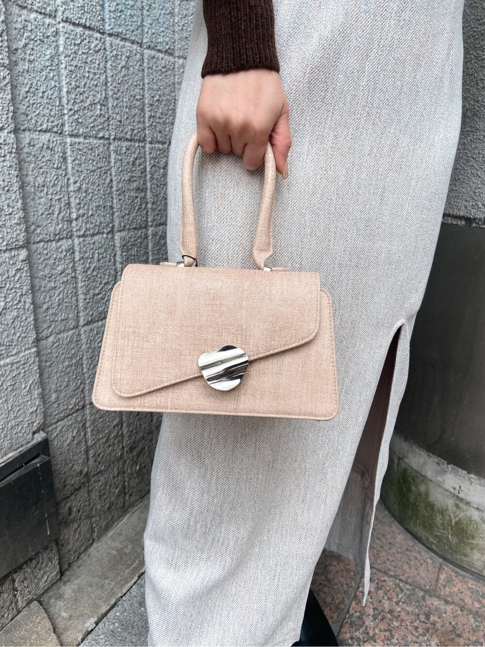 ホワイト系のスカート、ベージュ系のハンドバッグ、ブラウン系のカーディガン/ボレロを着用したレディースの冬コーディネートの7枚目の写真