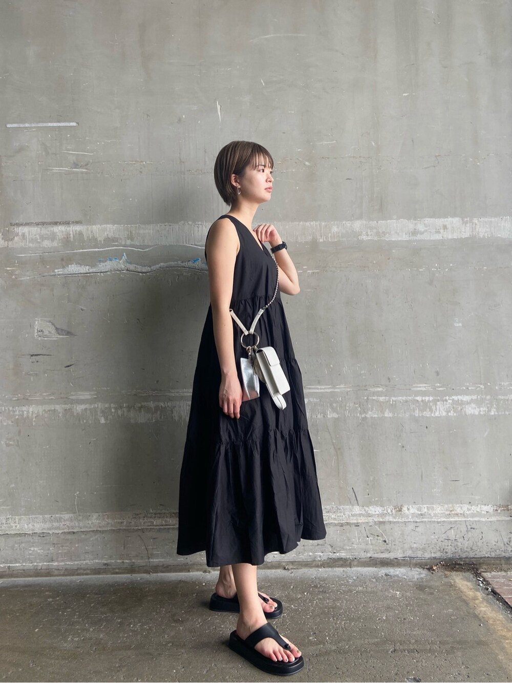 ブラック系のサンダル、ホワイト系のショルダーバッグ、ブラック系のワンピースを着用したレディースの夏コーディネートの2枚目の写真