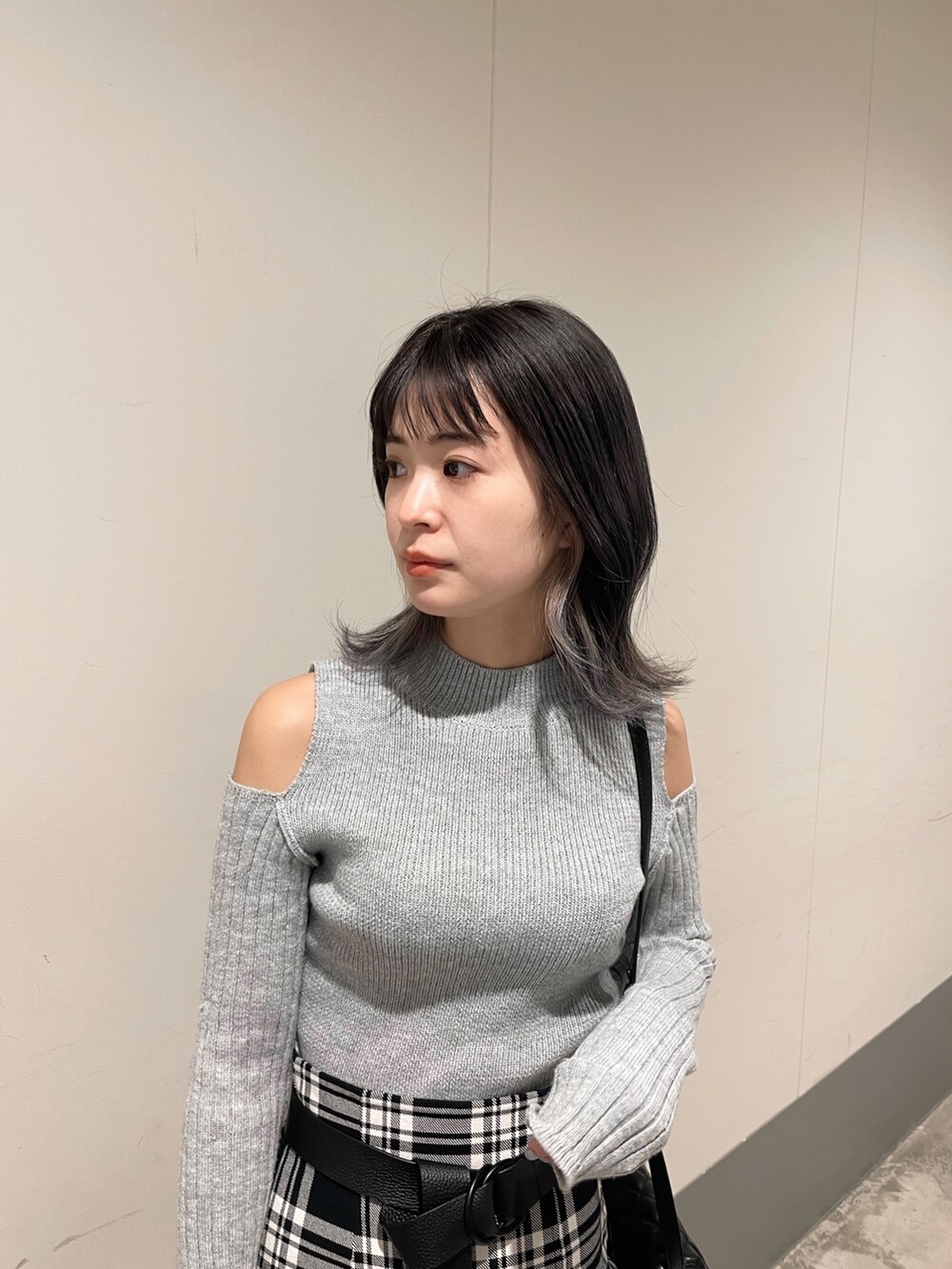 ブラック系のブーツ、グレー系のニット/セーター、ブラック系のスカートを着用したレディースの冬コーディネートの2枚目の写真