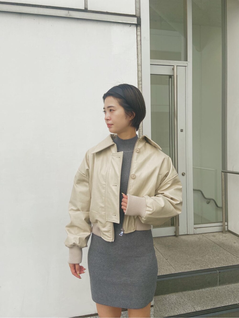 ホワイト系のブルゾン、グレー系のワンピースを着用したレディースの秋コーディネートの2枚目の写真