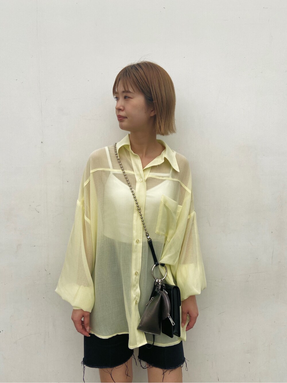 イエロー系のシャツ/ブラウス、ブラック系のサンダル、ブラック系のデニムパンツを着用したレディースの夏コーディネートの2枚目の写真