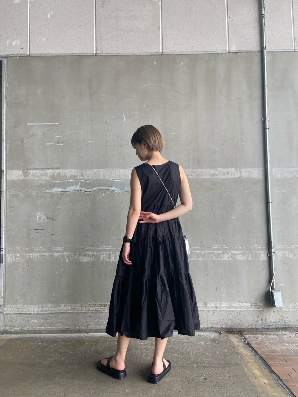 ブラック系のサンダル、ホワイト系のショルダーバッグ、ブラック系のワンピースを着用したレディースの夏コーディネートの3枚目の写真