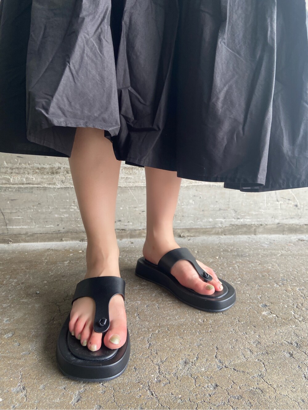 ブラック系のサンダル、ホワイト系のショルダーバッグ、ブラック系のワンピースを着用したレディースの夏コーディネートの7枚目の写真