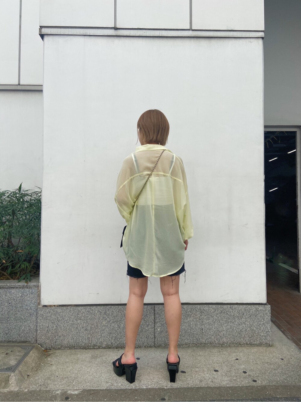 イエロー系のシャツ/ブラウス、ブラック系のサンダル、ブラック系のデニムパンツを着用したレディースの夏コーディネートの6枚目の写真