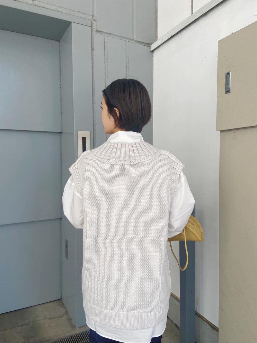 ホワイト系のシャツ/ブラウス、ホワイト系のベスト、イエロー系のハンドバッグを着用したレディースの秋コーディネートの3枚目の写真
