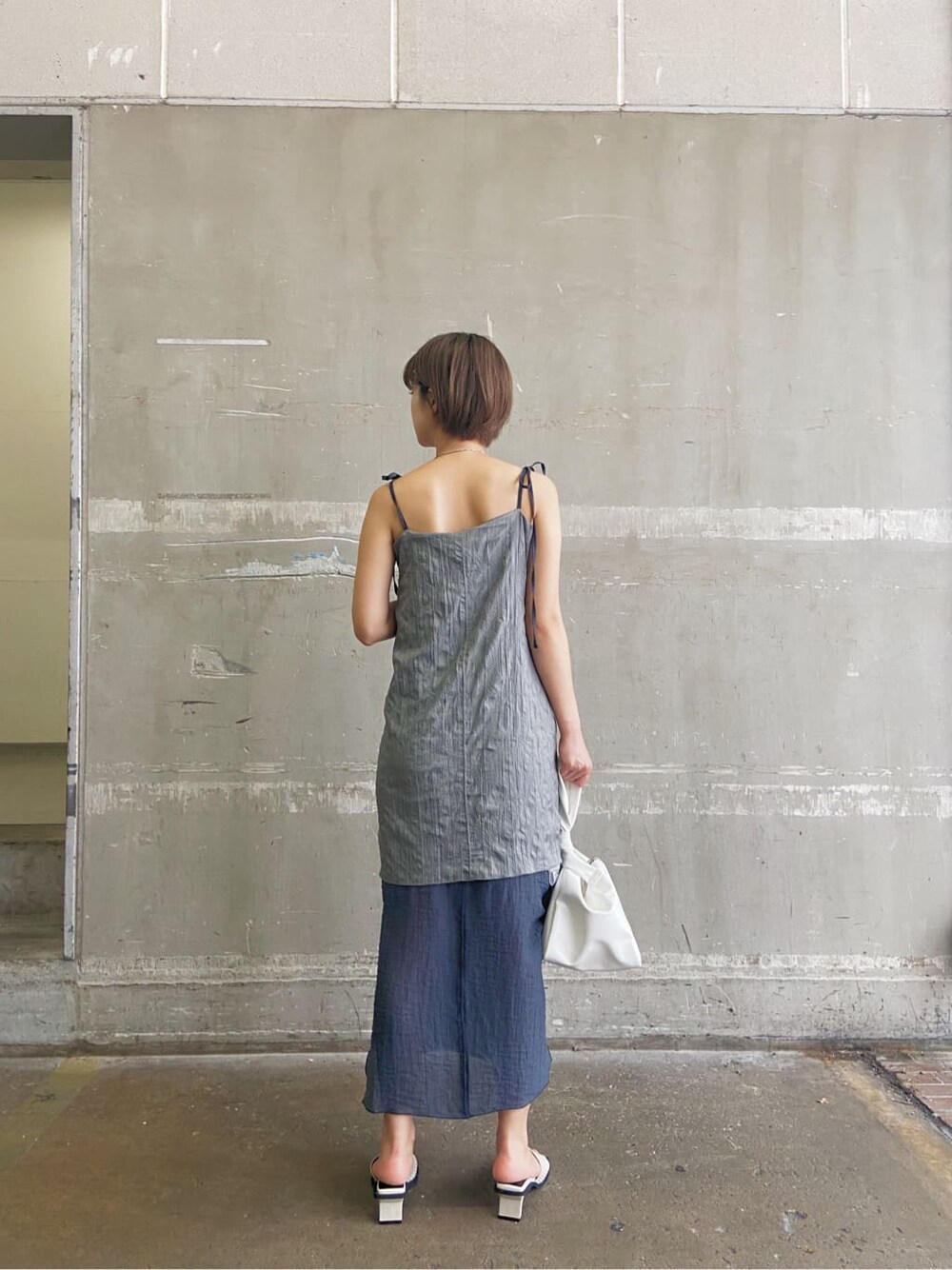 グレー系のワンピース、ホワイト系のサンダル、ホワイト系のハンドバッグを着用したレディースの夏コーディネートの2枚目の写真