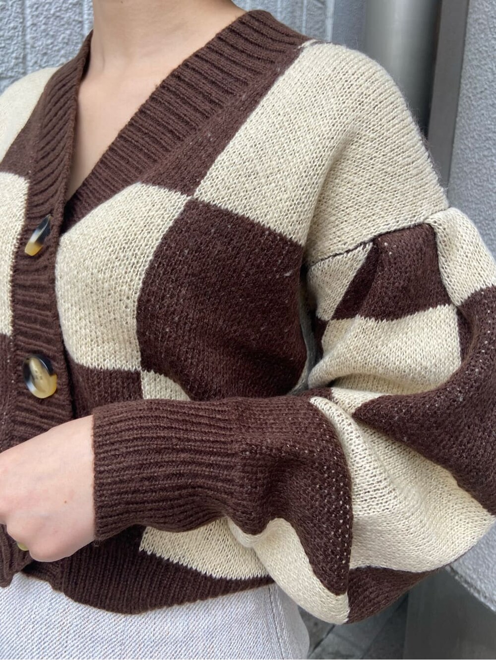 ホワイト系のスカート、ベージュ系のハンドバッグ、ブラウン系のカーディガン/ボレロを着用したレディースの冬コーディネートの4枚目の写真