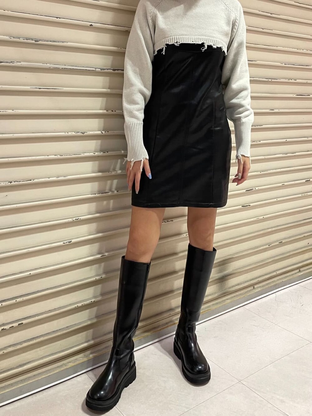 ブラック系のワンピース、ブラック系のブーツ、ホワイト系のニット/セーターを着用したレディースの秋コーディネートの2枚目の写真