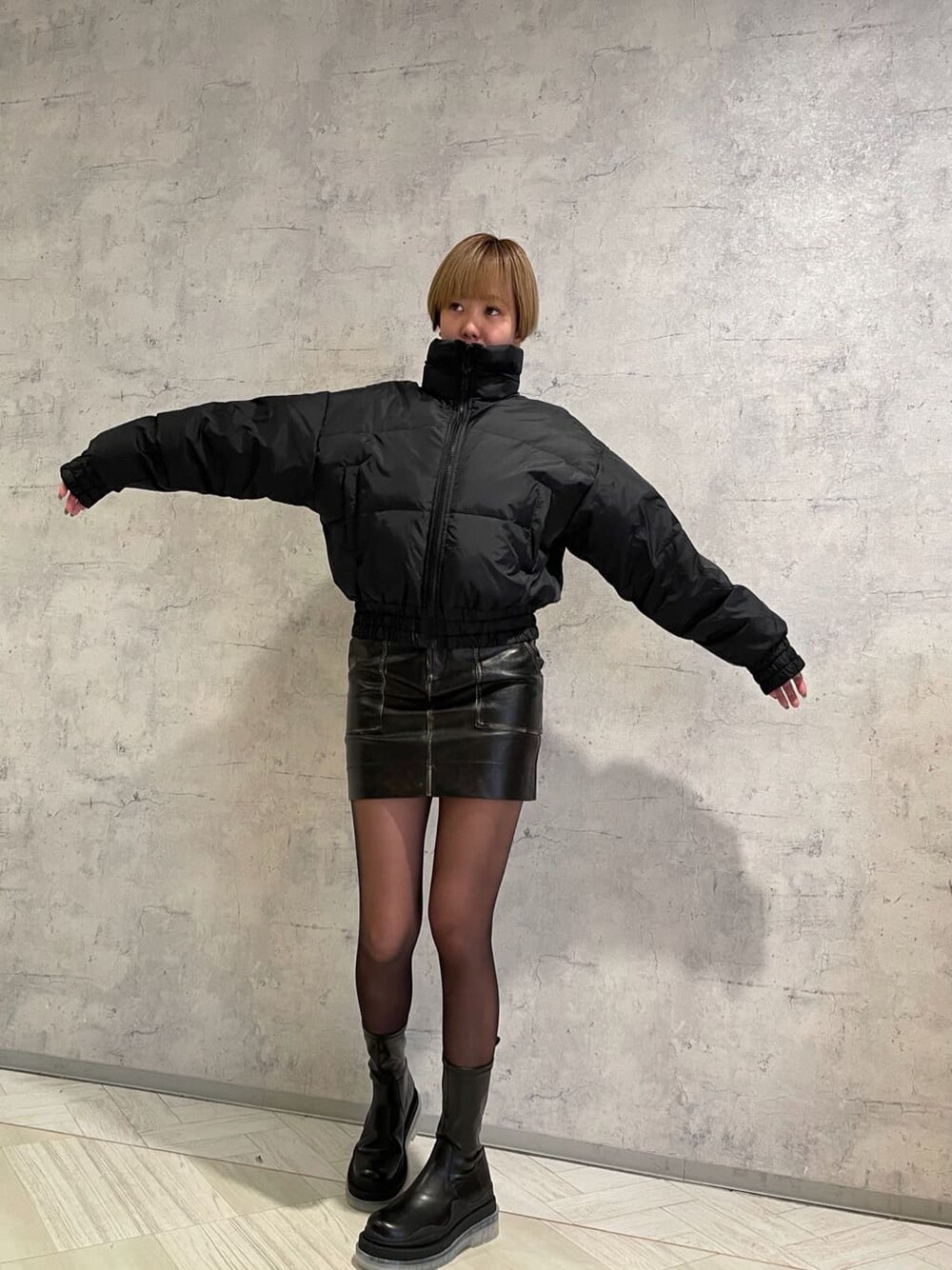 ブラック系のブーツ、ブラック系のスカート、ブラック系のダウンジャケット/コートを着用したレディースの冬コーディネートの4枚目の写真