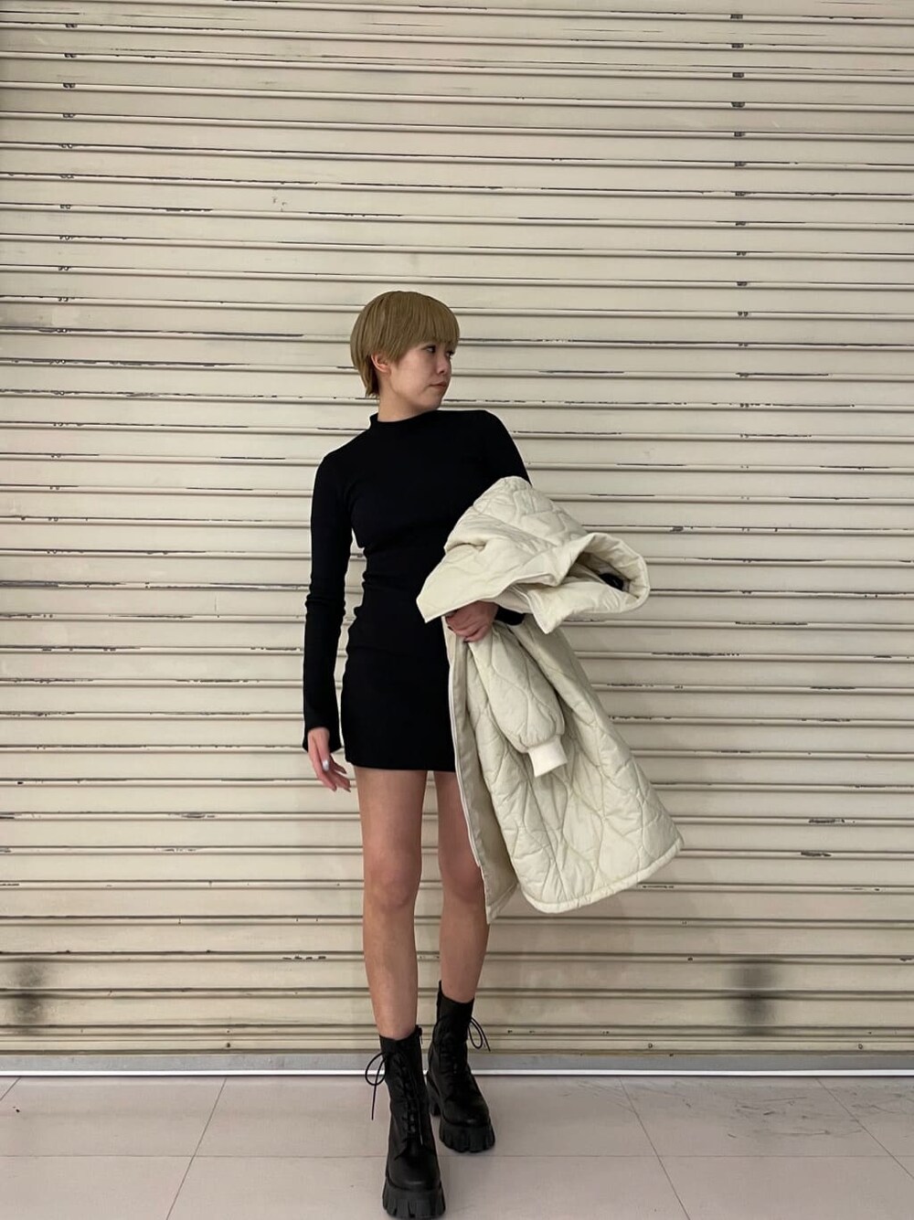 ブラック系のワンピース、ホワイト系のモッズコート、ブラック系のブーツを着用したレディースの春コーディネートの5枚目の写真