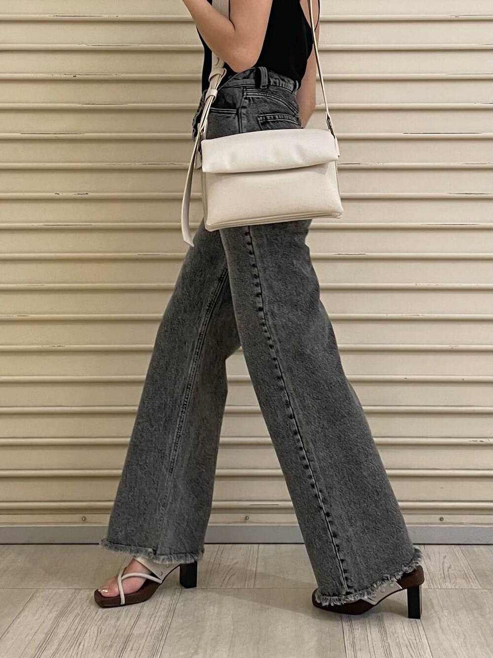 ホワイト系のショルダーバッグ、ホワイト系のサンダル、ブラック系のデニムパンツを着用したレディースの夏コーディネートの4枚目の写真