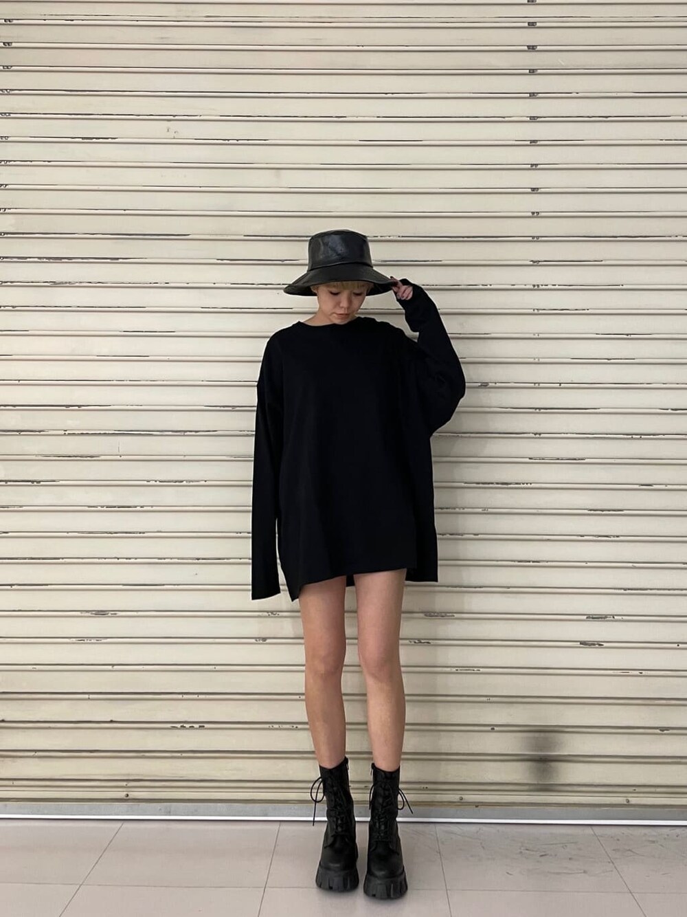 ブラック系のブーツ、ブラック系のTシャツ/カットソー、ブラック系のハットを着用したレディースの冬コーディネートの2枚目の写真