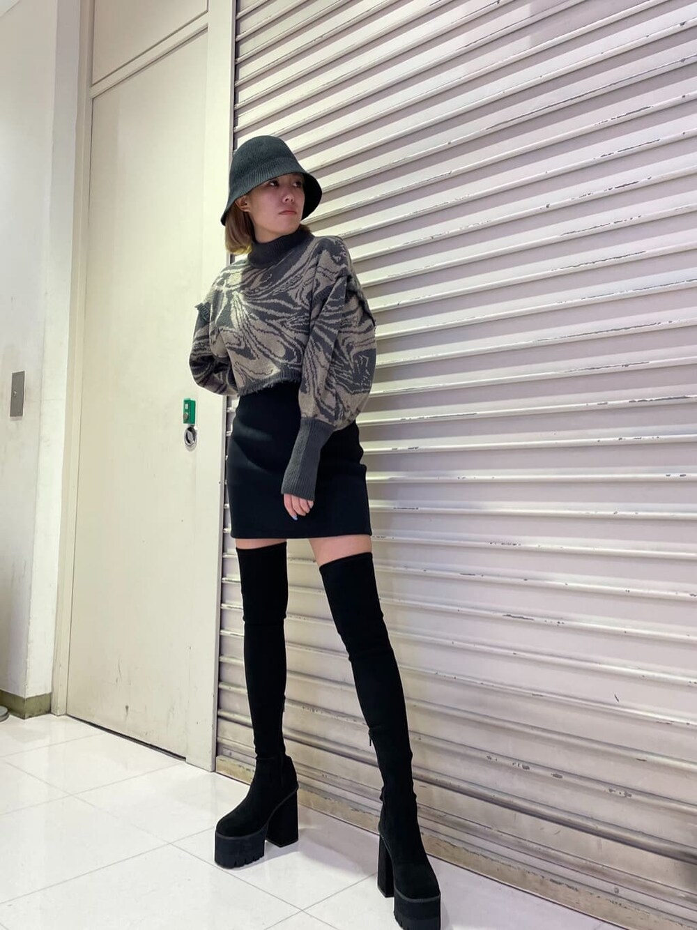 ブラック系のスカート、ブラック系のブーツ、その他のニット/セーターを着用したレディースの秋コーディネートの2枚目の写真