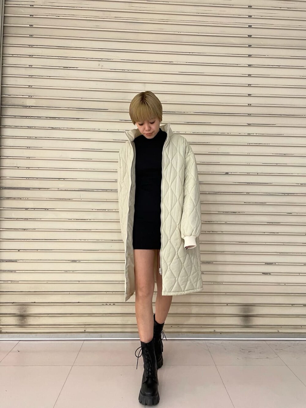 ホワイト系のモッズコート、ブラック系のワンピース、ブラック系のブーツを着用したレディースの春コーディネートの2枚目の写真