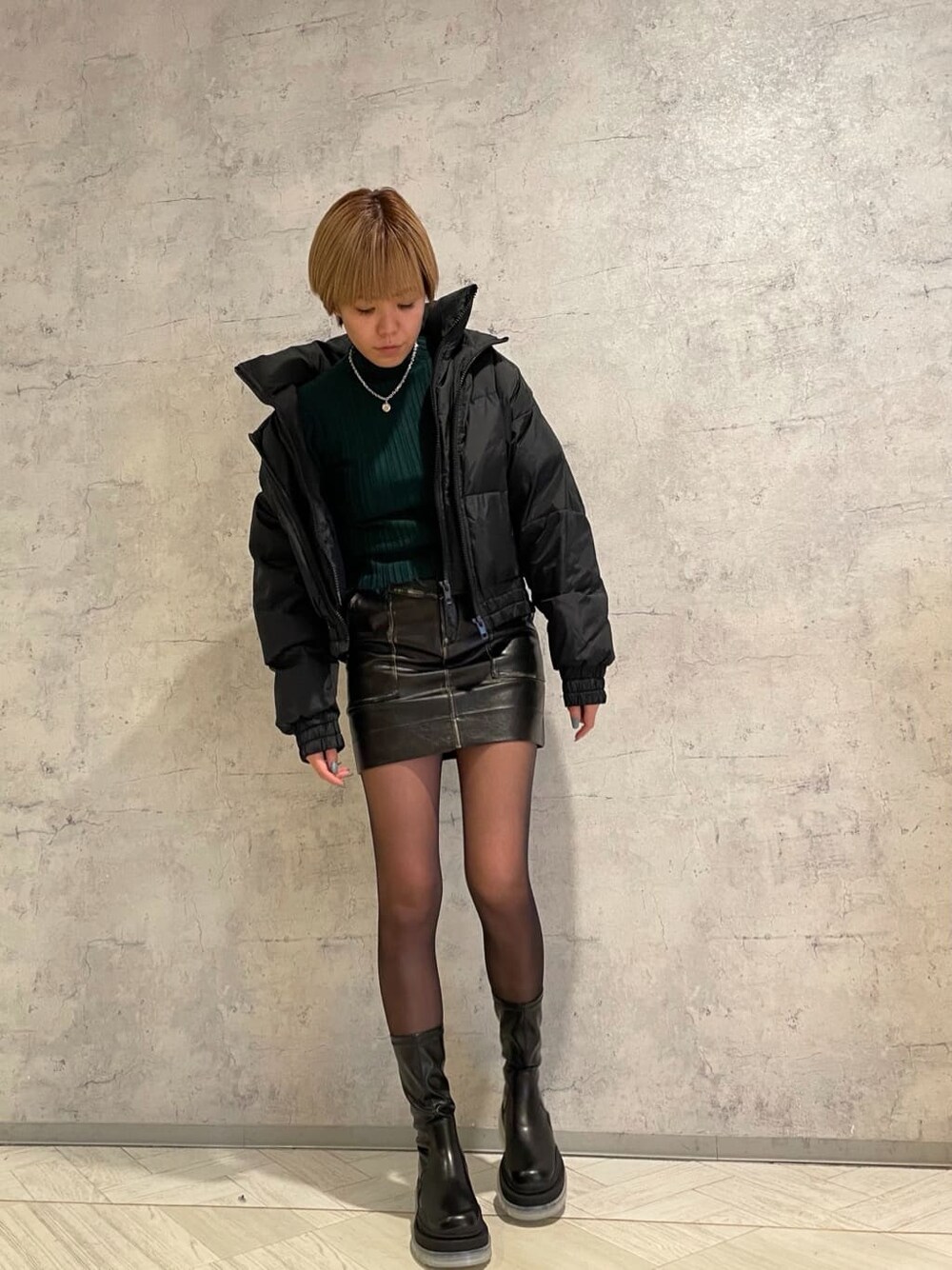 ブラック系のブーツ、ブラック系のスカート、ブラック系のダウンジャケット/コートを着用したレディースの冬コーディネートの2枚目の写真