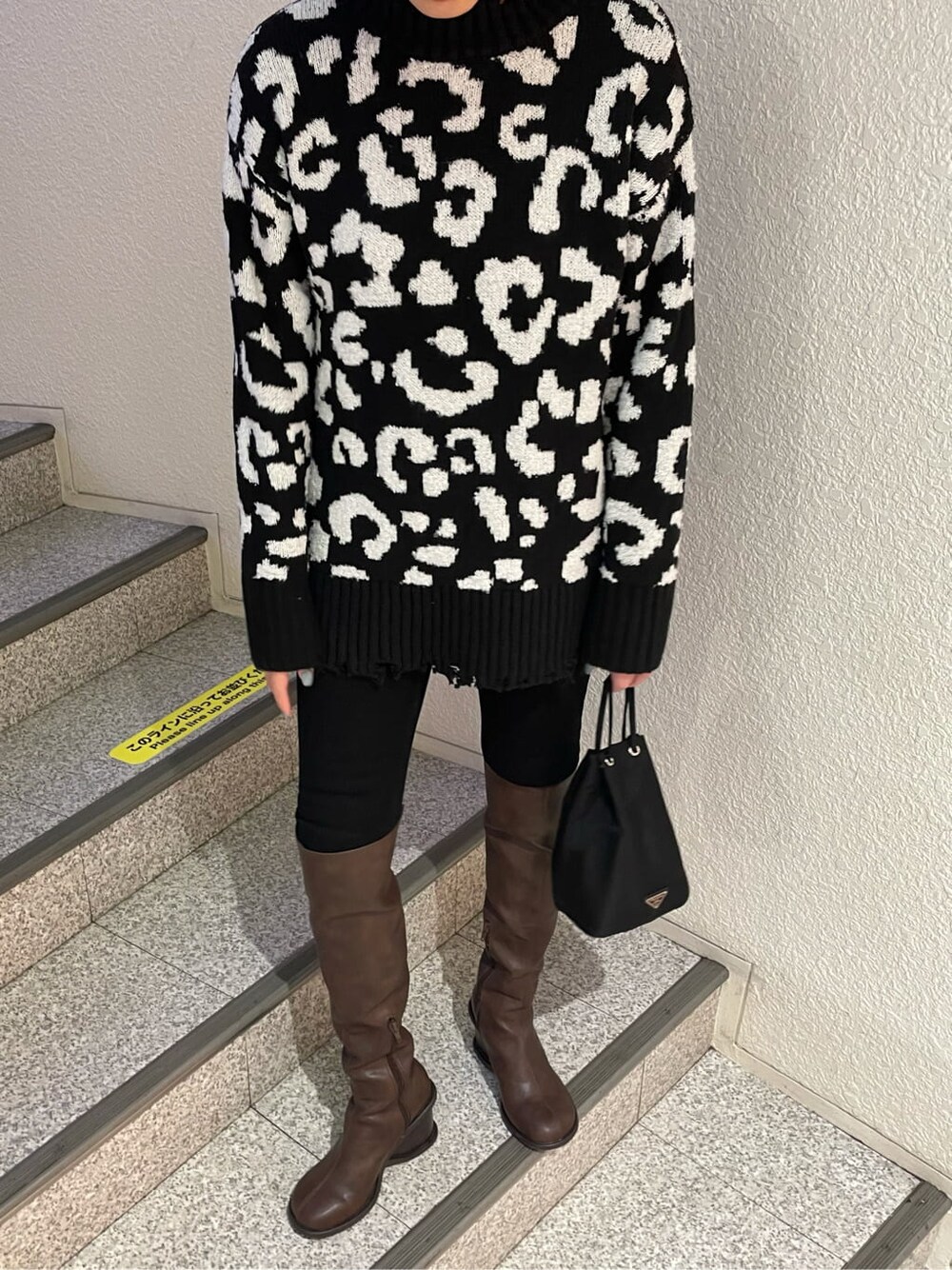 ブラック系のデニムパンツ、ブラウン系のブーツ、ブラック系のニット/セーターを着用したレディースの冬コーディネートの5枚目の写真