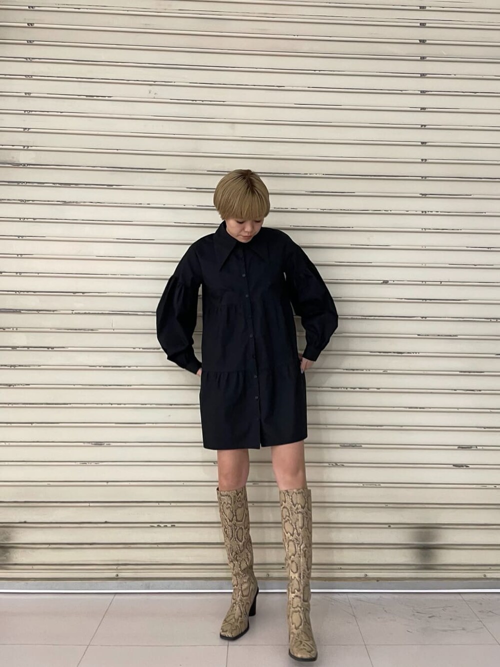 ブラック系のシャツワンピース、ブラック系のブーツを着用したレディースの春コーディネートの2枚目の写真