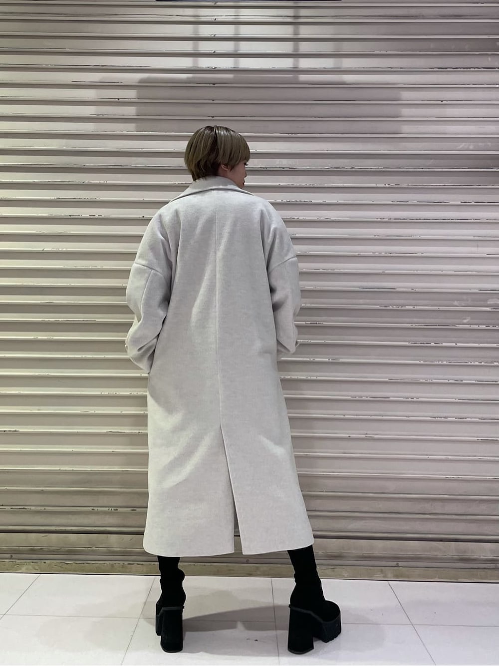 ホワイト系のチェスターコート、ブラック系のスカート、ブラック系のブーツを着用したレディースの冬コーディネートの4枚目の写真