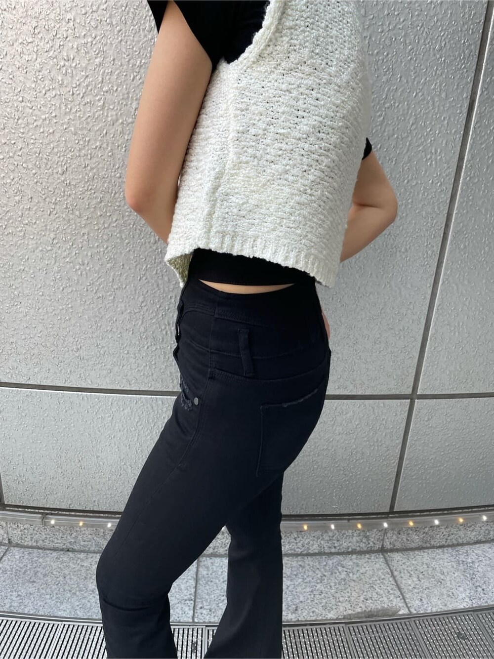 ブラック系のデニムパンツ、ホワイト系のベスト、ブラック系のサンダルを着用したレディースの夏コーディネートの5枚目の写真