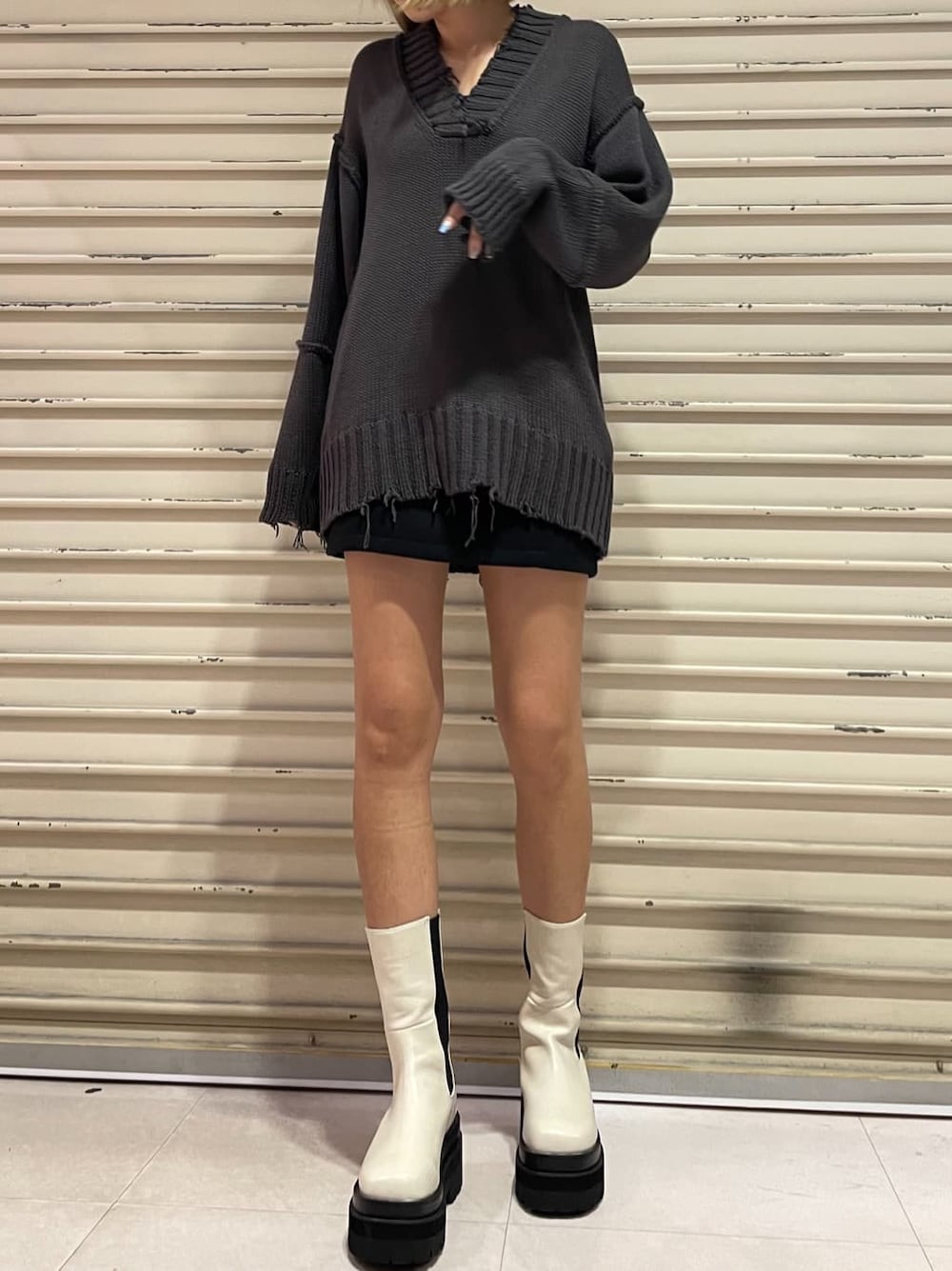 ブラック系のスカート、グレー系のニット/セーターを着用したレディースの秋コーディネートの2枚目の写真