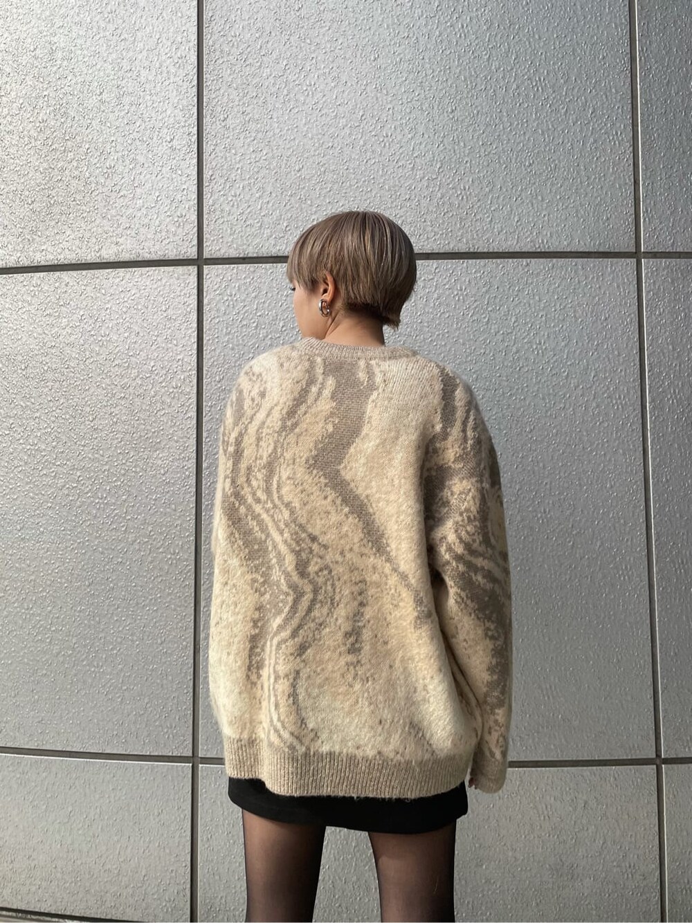 ベージュ系のニット/セーター、ブラック系のスカート、ブラック系のブーツを着用したレディースの冬コーディネートの5枚目の写真