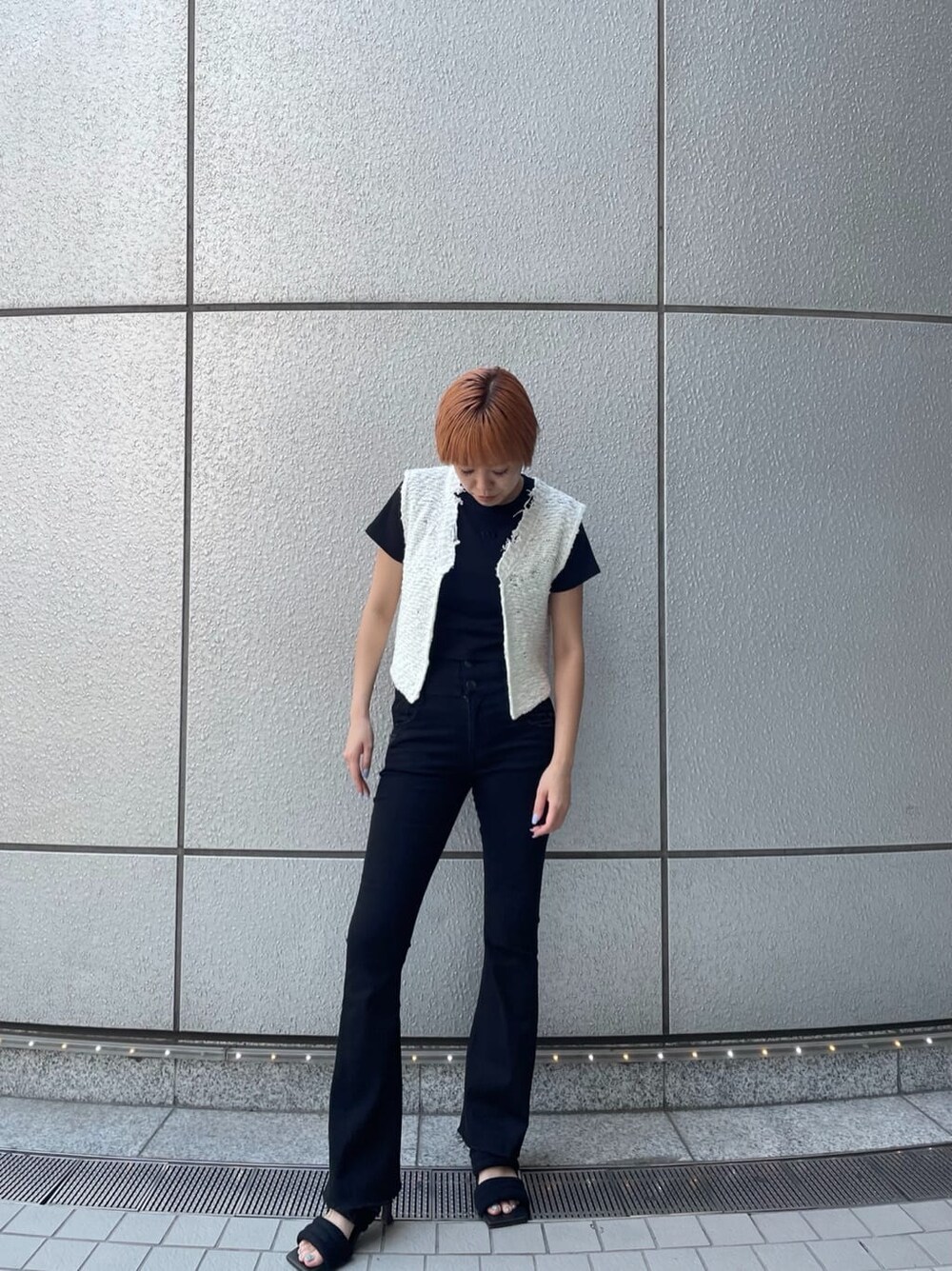 ブラック系のデニムパンツ、ホワイト系のベスト、ブラック系のサンダルを着用したレディースの夏コーディネートの3枚目の写真