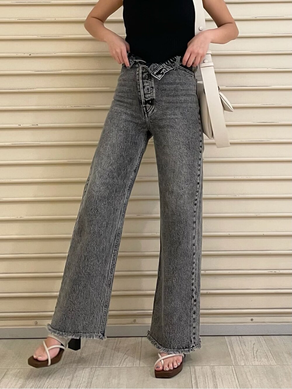 ホワイト系のショルダーバッグ、ホワイト系のサンダル、ブラック系のデニムパンツを着用したレディースの夏コーディネートの2枚目の写真