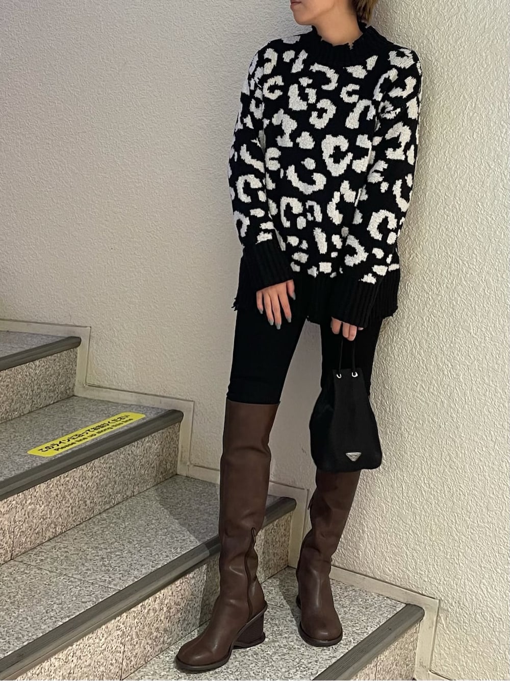 ブラック系のデニムパンツ、ブラウン系のブーツ、ブラック系のニット/セーターを着用したレディースの冬コーディネートの3枚目の写真