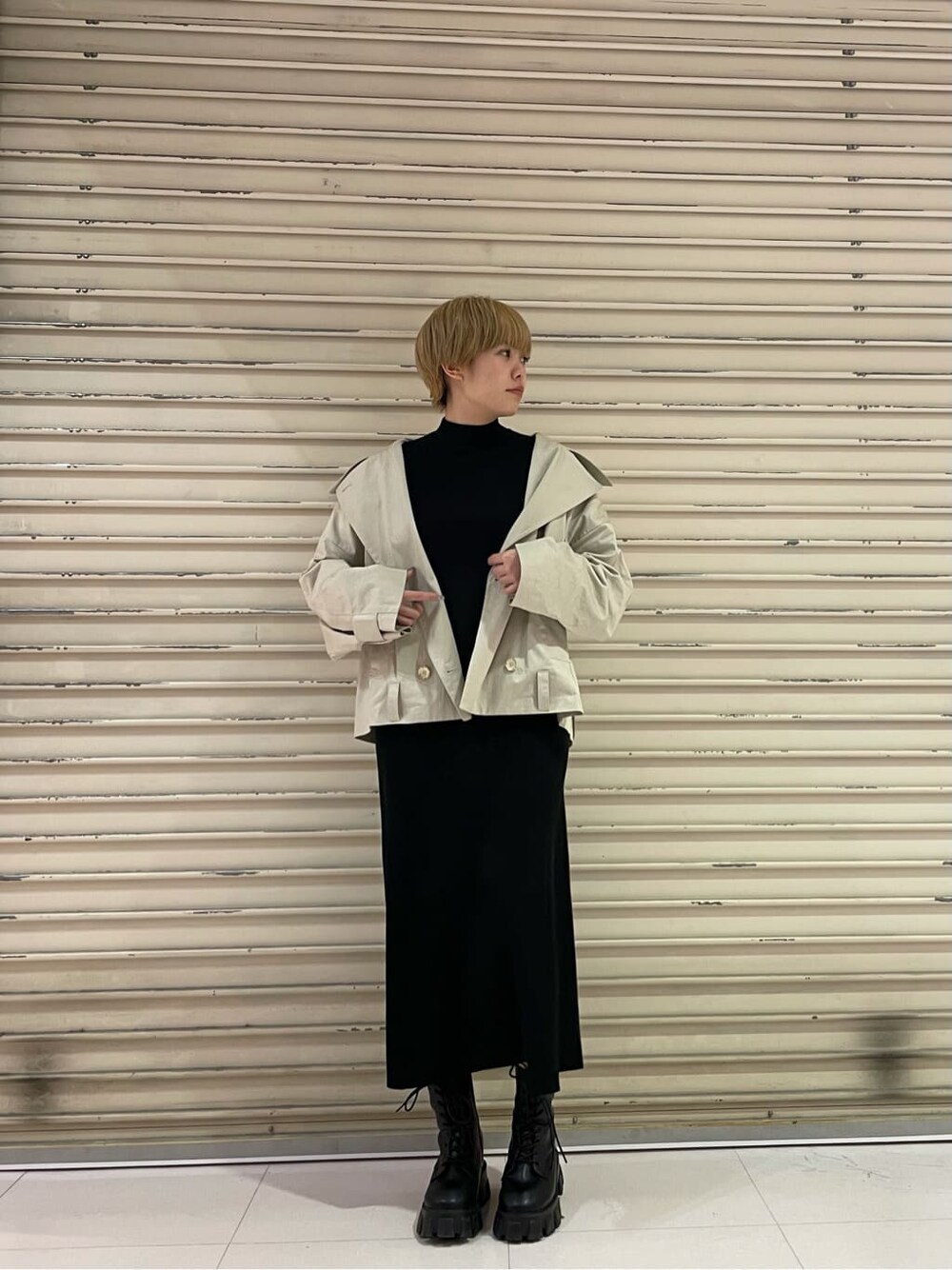 ブラック系のブーツ、ベージュ系のトレンチコート、ブラック系のワンピースを着用したレディースの冬コーディネートの2枚目の写真