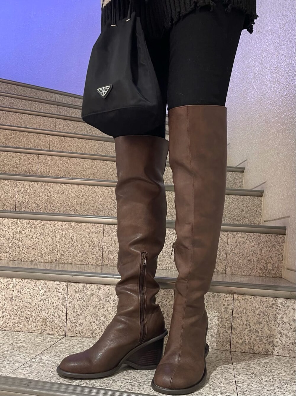 ブラック系のデニムパンツ、ブラウン系のブーツ、ブラック系のニット/セーターを着用したレディースの冬コーディネートの6枚目の写真