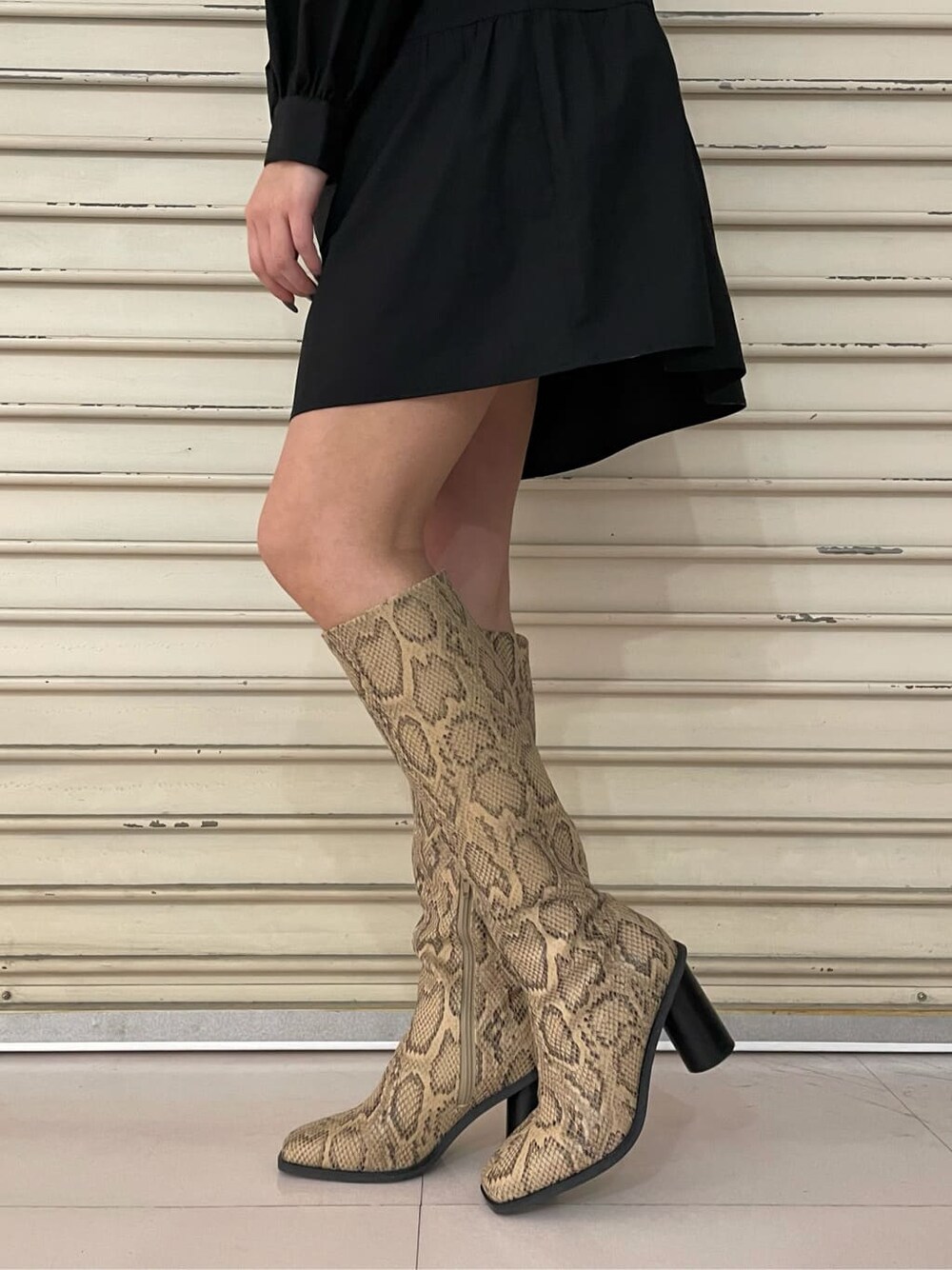 ブラック系のシャツワンピース、ブラック系のブーツを着用したレディースの春コーディネートの6枚目の写真