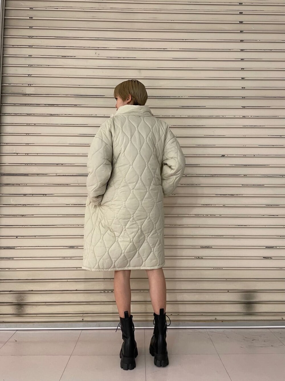 ホワイト系のモッズコート、ブラック系のワンピース、ブラック系のブーツを着用したレディースの春コーディネートの4枚目の写真