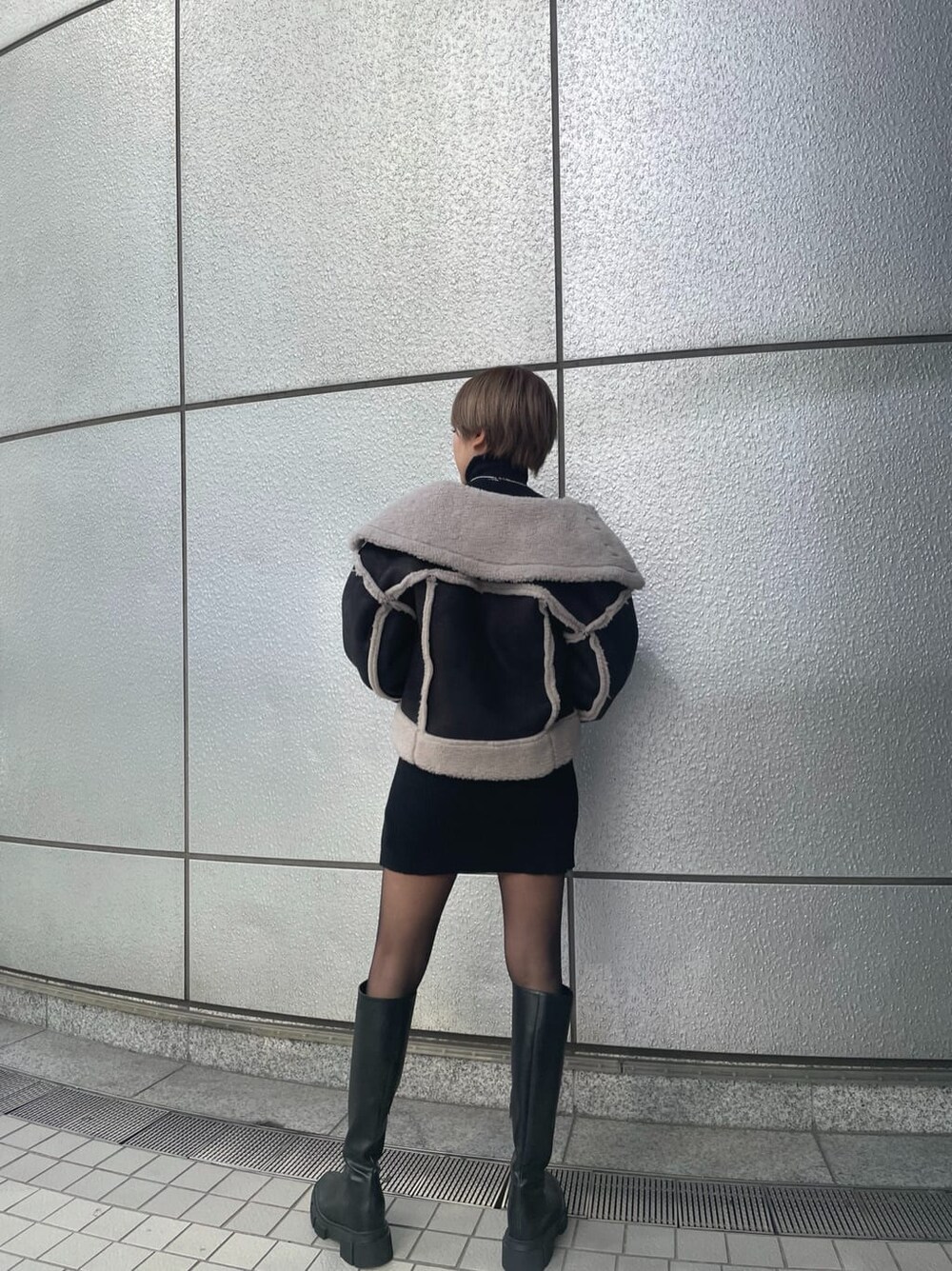 ブラック系のワンピース、その他のムートンコート、ブラック系のブーツを着用したレディースの冬コーディネートの3枚目の写真