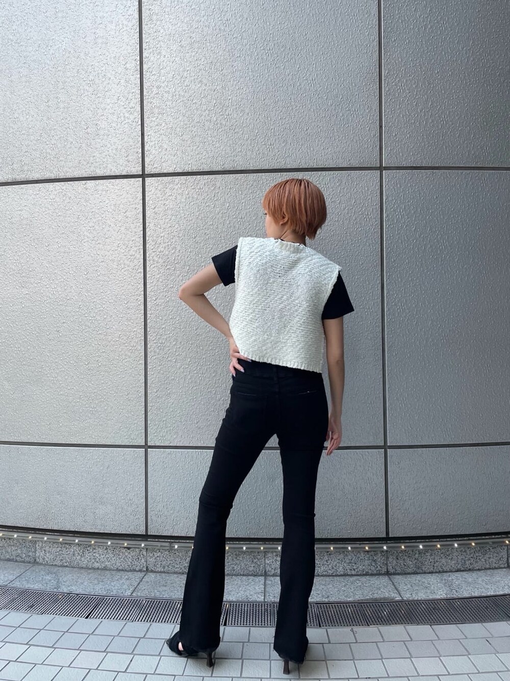 ブラック系のデニムパンツ、ホワイト系のベスト、ブラック系のサンダルを着用したレディースの夏コーディネートの4枚目の写真