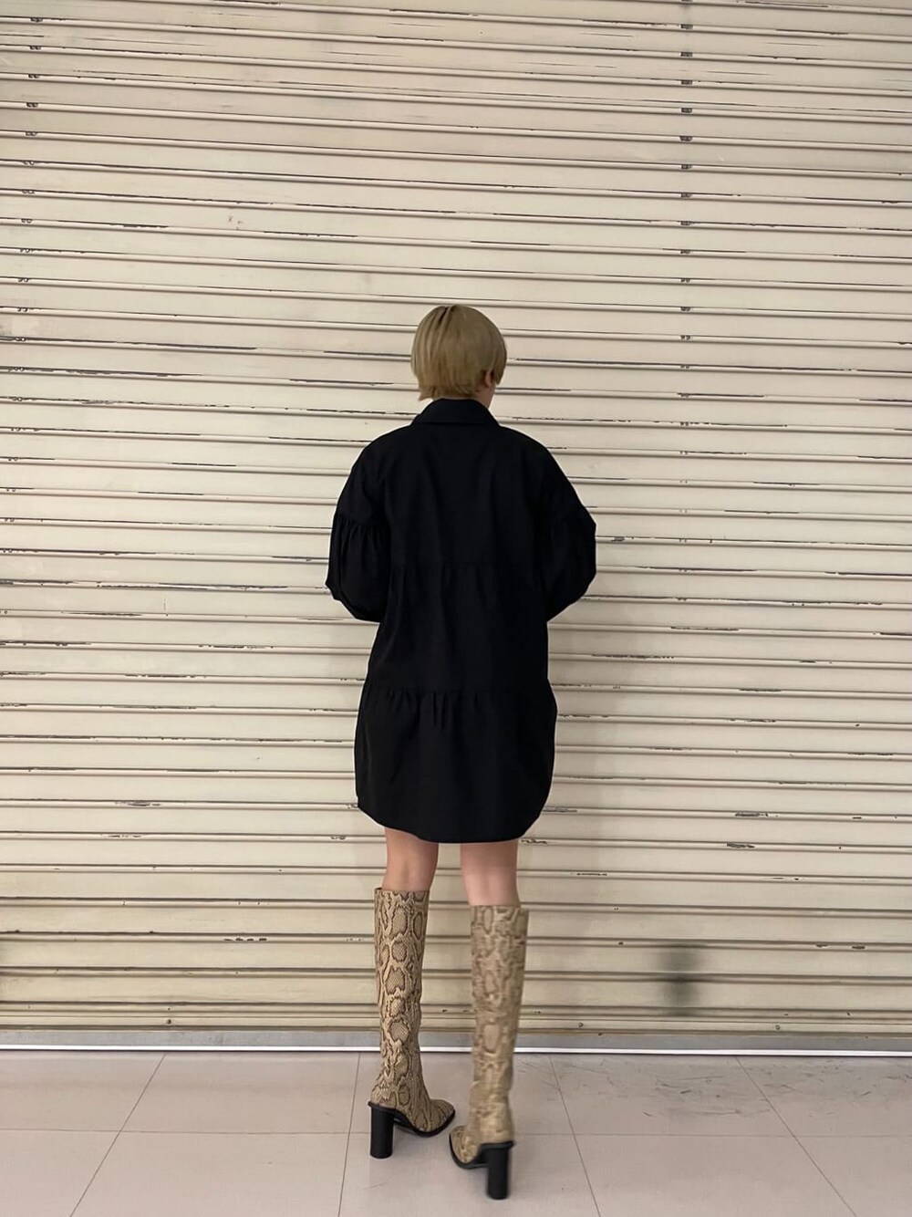 ブラック系のシャツワンピース、ブラック系のブーツを着用したレディースの春コーディネートの4枚目の写真