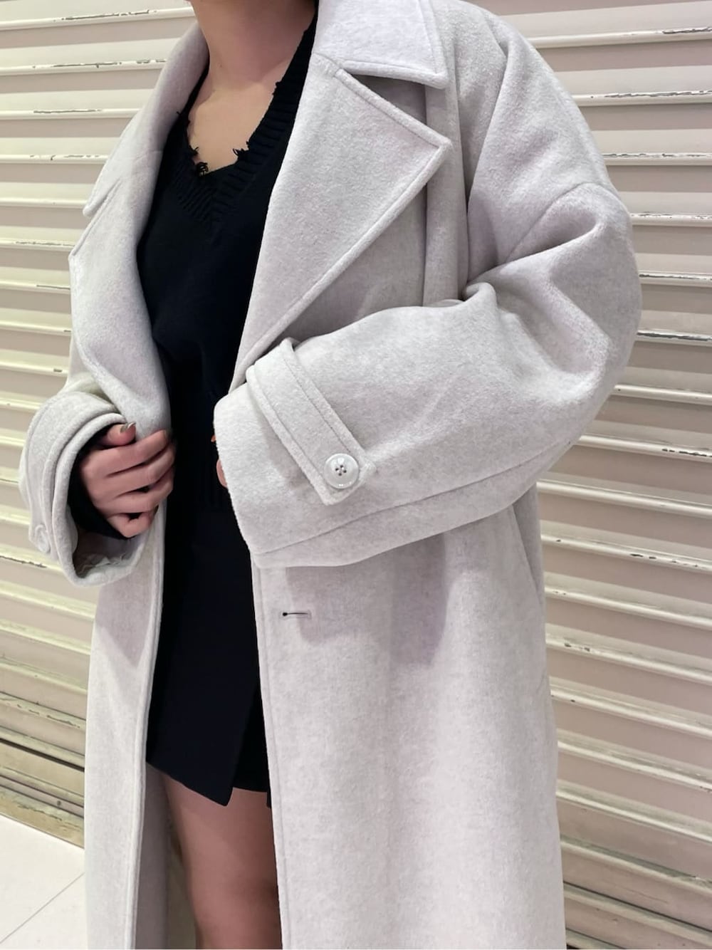 ホワイト系のチェスターコート、ブラック系のスカート、ブラック系のブーツを着用したレディースの冬コーディネートの5枚目の写真