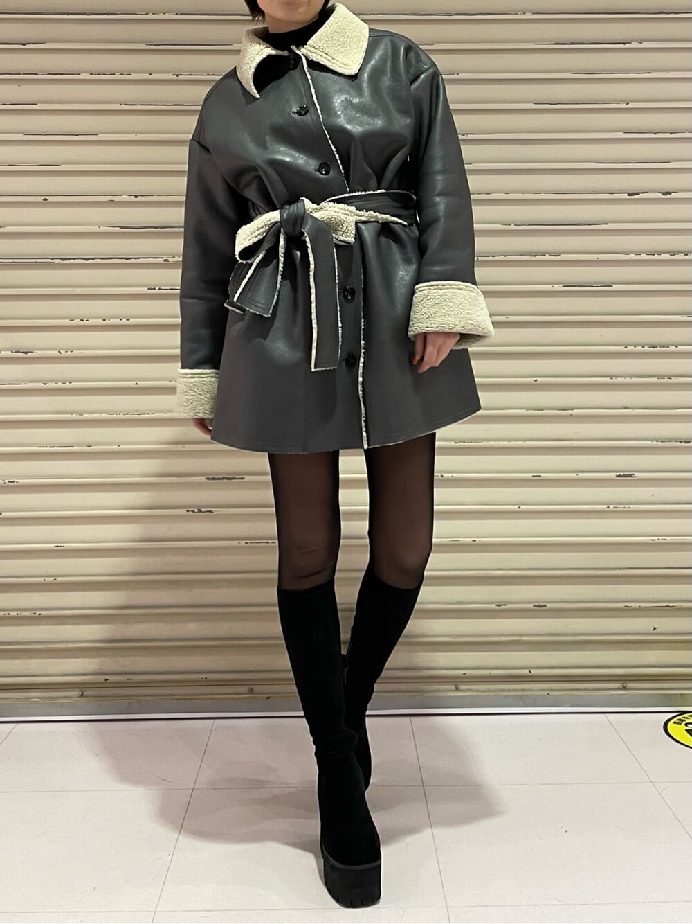 グレー系のムートンコート、ブラック系のブーツを着用したレディースの冬コーディネートの2枚目の写真