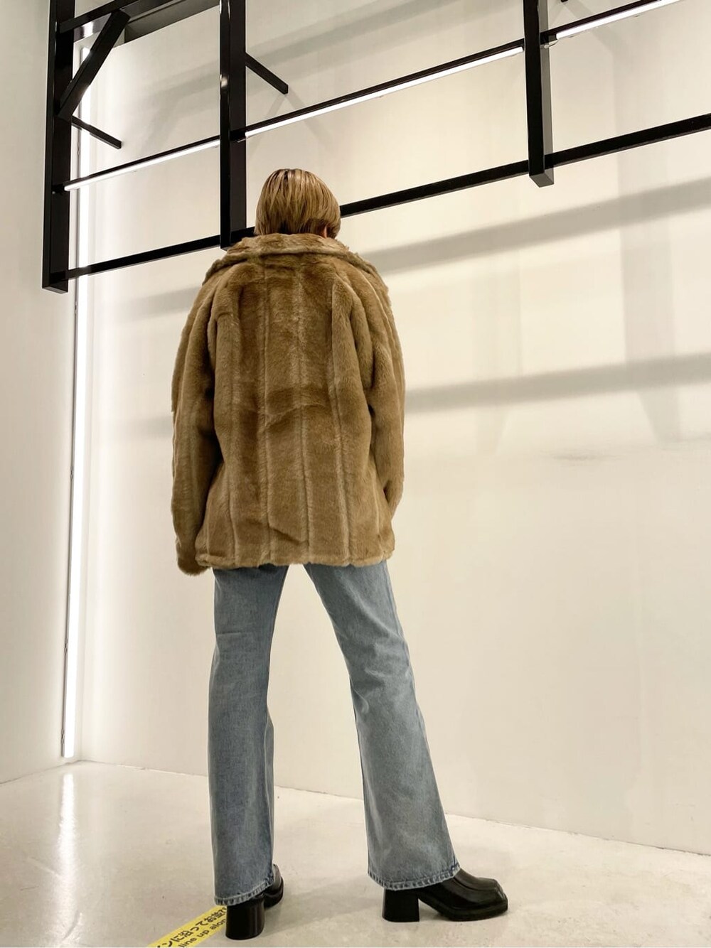 ブラック系のブーツ、ベージュ系のその他アウター、ブラック系のニット/セーターを着用したレディースの冬コーディネートの2枚目の写真