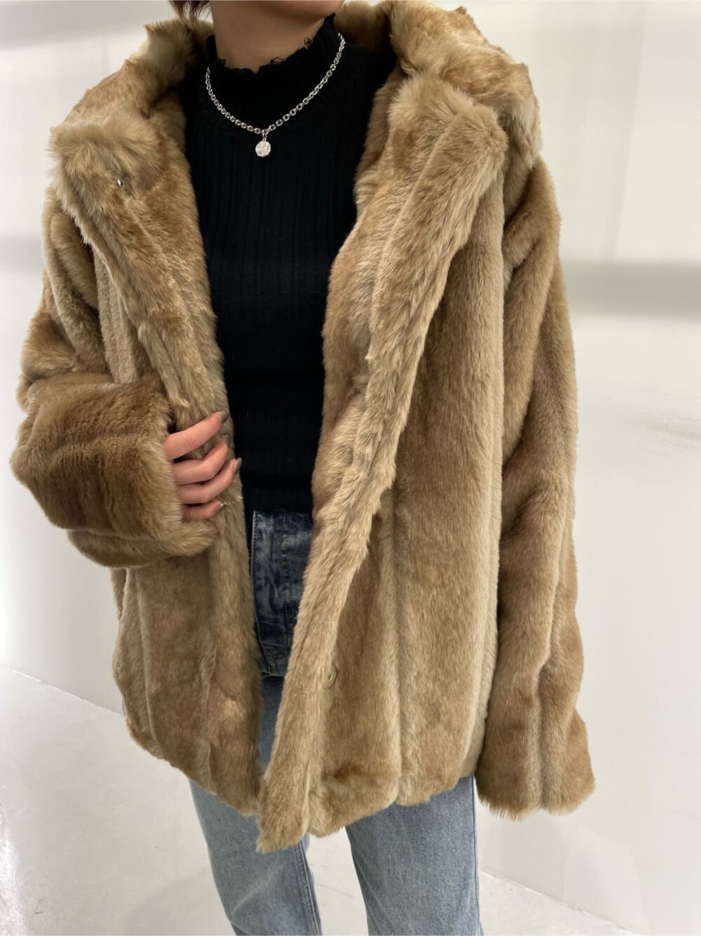 ブラック系のブーツ、ベージュ系のその他アウター、ブラック系のニット/セーターを着用したレディースの冬コーディネートの3枚目の写真