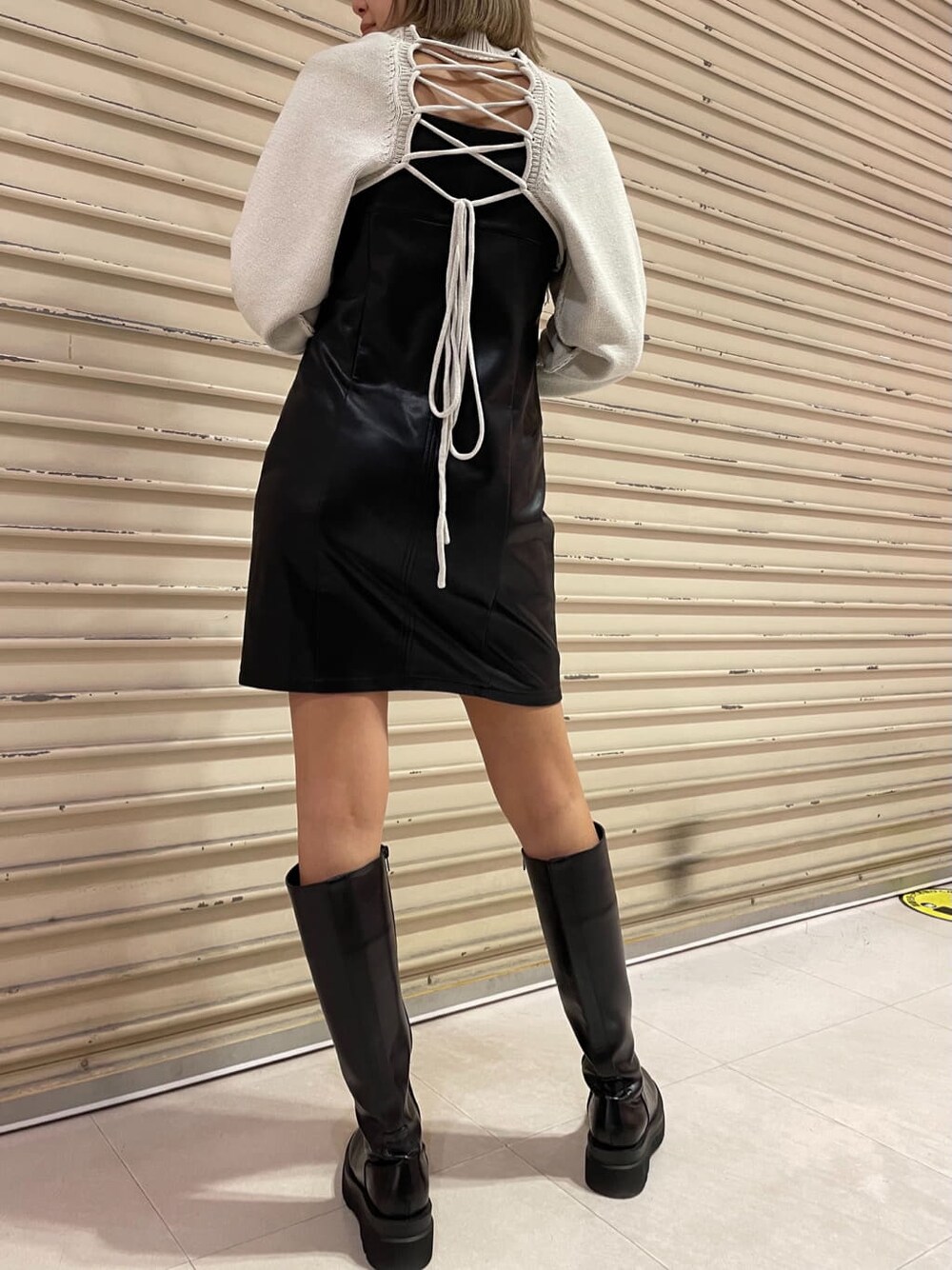 ブラック系のワンピース、ブラック系のブーツ、ホワイト系のニット/セーターを着用したレディースの秋コーディネートの3枚目の写真