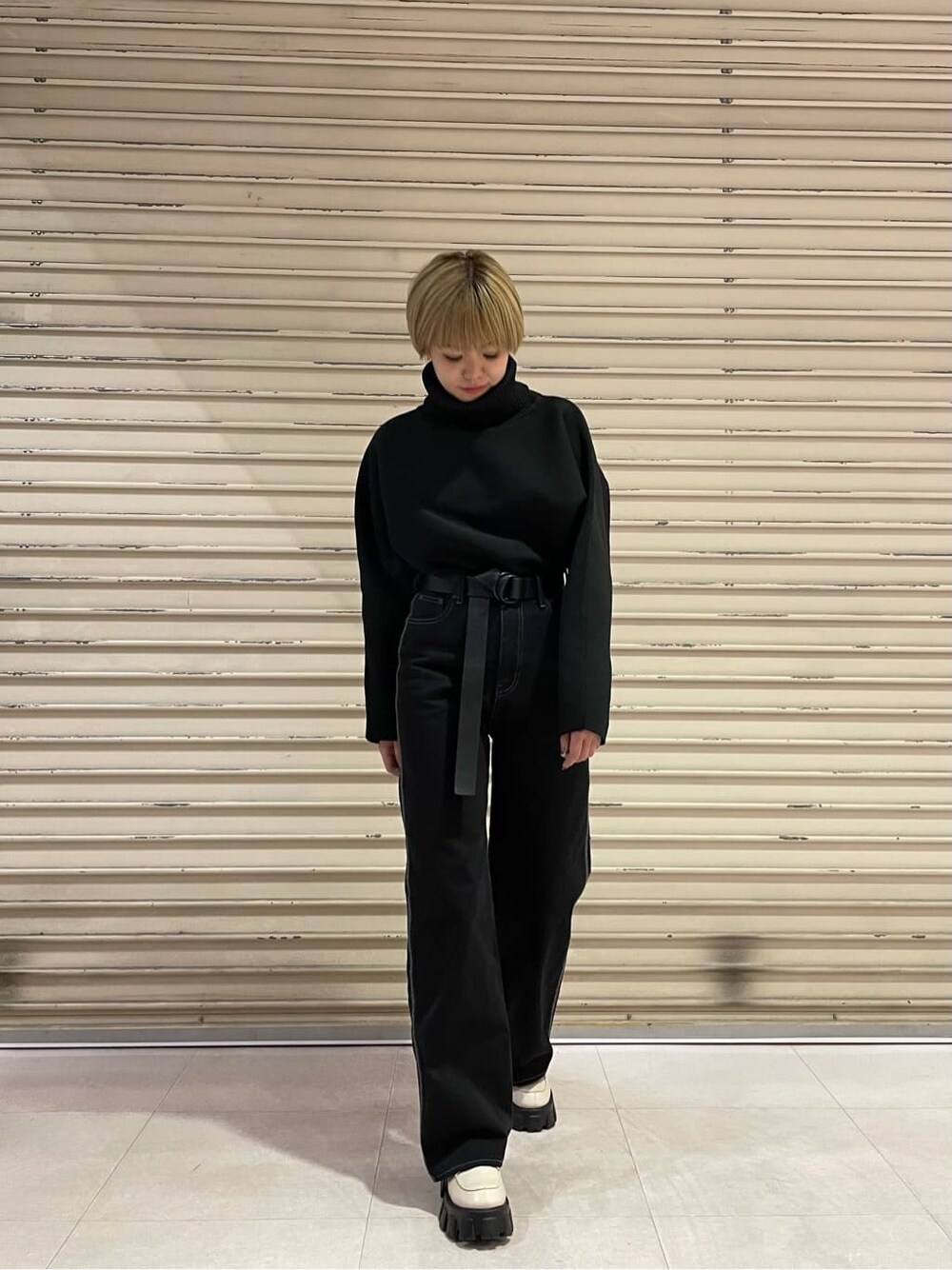 ブラック系のデニムパンツ、ブラック系のニット/セーター、ホワイト系のローファーを着用したレディースの秋コーディネートの2枚目の写真