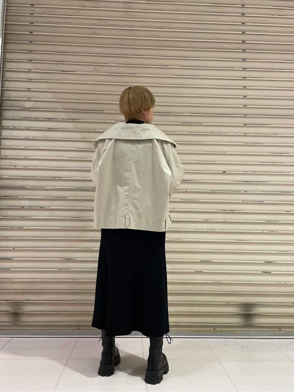 ブラック系のブーツ、ベージュ系のトレンチコート、ブラック系のワンピースを着用したレディースの冬コーディネートの4枚目の写真