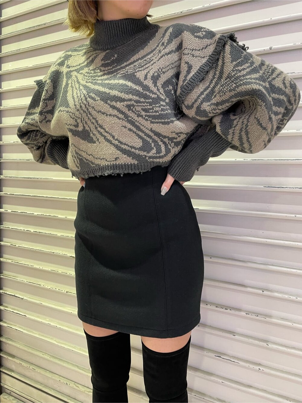 ブラック系のスカート、ブラック系のブーツ、その他のニット/セーターを着用したレディースの秋コーディネートの4枚目の写真