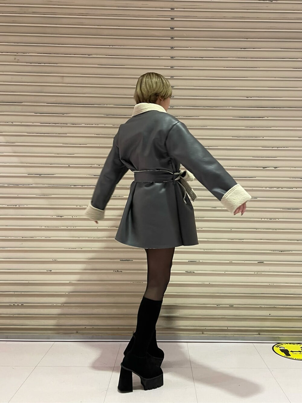 グレー系のムートンコート、ブラック系のブーツを着用したレディースの冬コーディネートの3枚目の写真